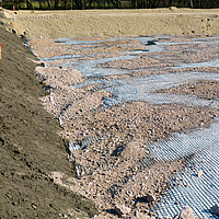 Geogriglia Basetrac Grid in un cantiere, su cui è già stata sparsa sabbia o ghiaia in alcuni punti.