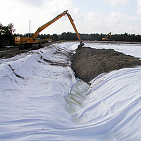 L'escavatore stende il terreno sul geocomposito Basetrac® Duo