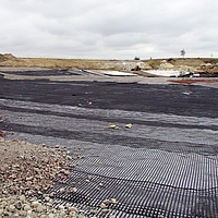 Geogriglia Basetrac Grid in uso per rinforzare lo strato di base in un cantiere.