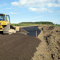 Un bulldozer stende il terreno su una griglia Basetrac già posata in cantiere