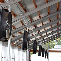 Vista laterale di diversi ventilatori assiali in una stalla per mucche