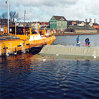 Gli operai installano materiali geotessili per la protezione del fondale del porto