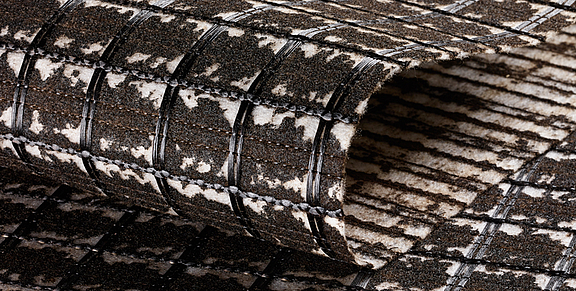 Armatura per asfalto SamiGrid® - primo piano del materiale  Il composito SamiGrid® di griglia in PVA e tessuto non tessuto saturo di bitume in primo piano